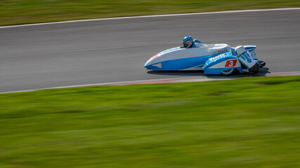 A panning shot of a racing sidecar as it corners on a track.