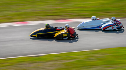 A panning shot of a racing sidecar as it corners on a track.