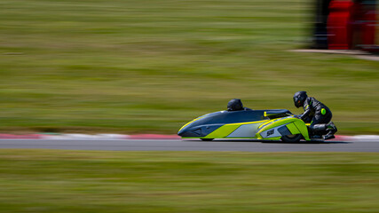 A panning shot of a racing sidecar as it corners on a track.