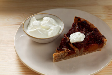 Piece of quince stuffed pie served with yoghurt. Close-up view of homemade dessert.