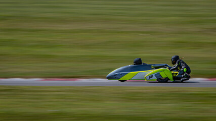 A panning shot of a racing sidecar as it corners on a track.
