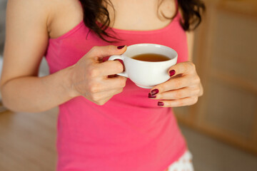 a mug of tea in the hands of a young woman 