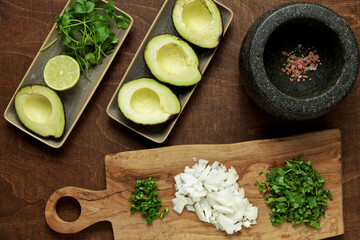 Preparing classic guacamole dish with fresh ingredients: hass avocado, onion, coriander, chili pepper, salt and lime juice.