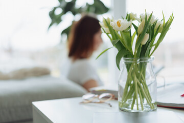 Glass jar with bunch of white spring tulips indoors