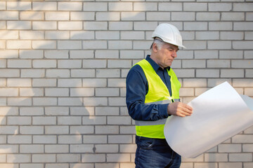 Engineer construction foreman manager at a construction site with blueprints