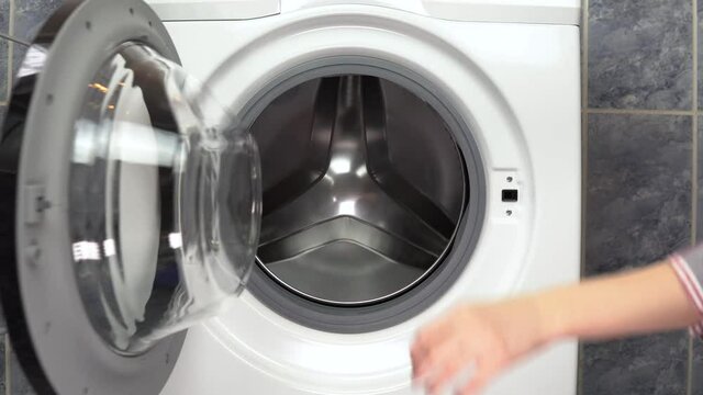 A young woman loads clothes with a washing machine