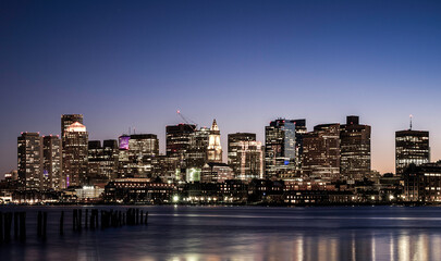 Boston Skyline over the Boston Harbor in Massachusetts at Dusk. Modern City Nightscape with Water Reflections.