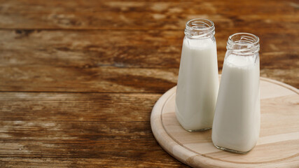 Fresh milk in two glass bottles. Wood rustic background