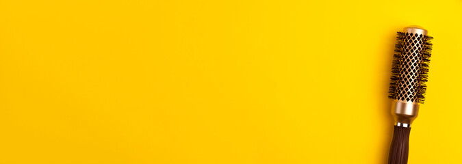 Banner template flat lay of gold round hair brush for styling on yellow background Hairdresser salon equipment concept with copy space