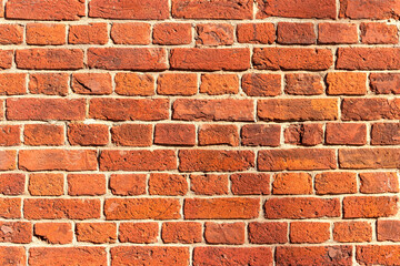 A wall of old, cracked bricks, with a weathered and faded surface. Restored brickwork of an old house.