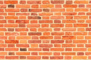 A wall of old, cracked bricks, with a weathered and faded surface. Restored brickwork of an old house.