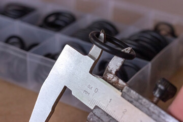 Measuring the diameter of the rubber O-ring with a caliper. An old measuring tool and a set of...