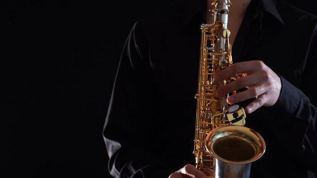 Closeup of hands playing on saxophone isolated on black background 