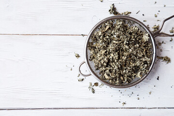 Dry raspberry leaves in a tea strainer close-up. Alternative herbal medicine. Healthy lifestyle...