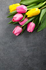 Fresh tulips bouquet lying on a dark grey stone surface