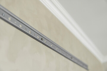 Close-up of stainless steel mounting rail for mounting kitchen cabinets on a wall.