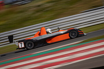 A panning shot of a racing car as it circuits a track.