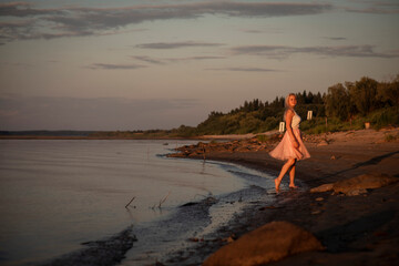 blonde girl on a river beach at sunset, selective focus