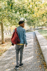 Young boy with afro hair walks through a park on an autumn day