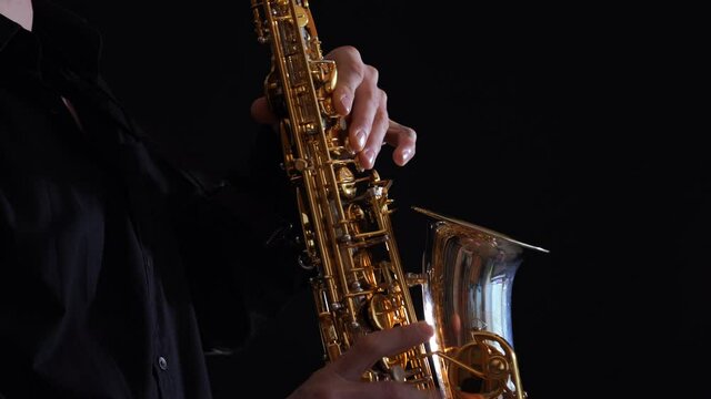 Closeup of hands playing on saxophone isolated on black background 
