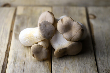 Raw eringi mushrooms on a wooden surface.