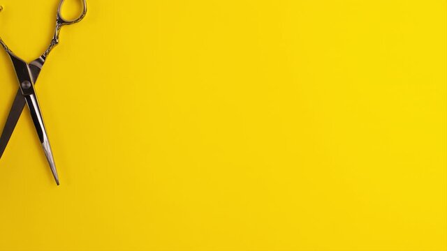 Stop motion animation template flat lay of professional hair cutting shears that cut in a circle on yellow background Hairdresser salon equipment concept with copy space Selfcare on lockdown time