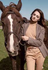 Beautiful brunette woman in an elegant checkered jacket with a horse