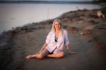 Fototapeta na wymiar blonde girl in white men's shirt on the beach, selective focus