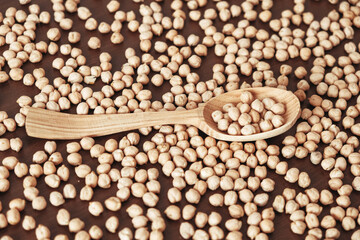 Raw chickpeas in a wooden spoon scattered on a wooden background. Top view. Copy, empty space for text