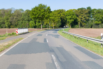 Fototapeta na wymiar Langgezogene Kurve einer Landstraße mit Radweg und Baumbestand