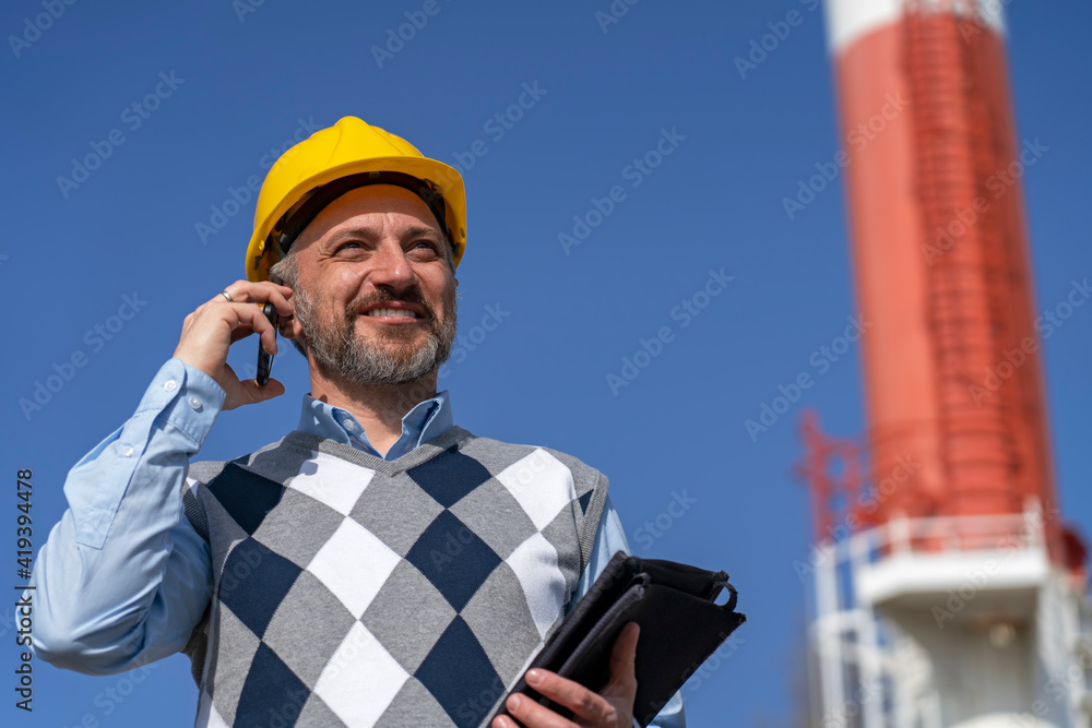 Wall mural portrait of smiling manager with mobile phone and digital tablet in district heating power plant