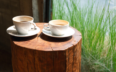 Closeup image of two cups of hot  coffee on wooden log,,