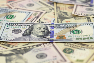 one hundred dollar bill lies on scattered dollar bills of different denominations, blurred background