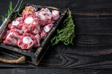 Raw veal beef Oxtail Meat in wooden tray with thyme. Black wooden background. Top view. Copy space