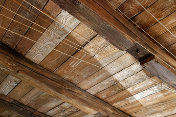 Stary strych. Dach z drewnianych belek i desek. Sznurki na bieliznę i lampa. - obrazy, fototapety, plakaty