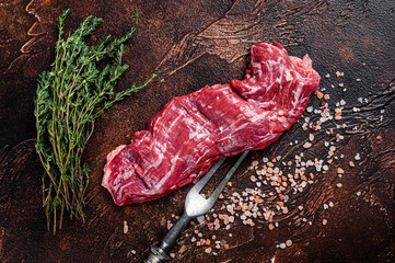 Raw machete skirt beef steak on meat fork. Dark background. Top view - obrazy, fototapety, plakaty