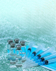Medical ampoules, syringes and a mask on a green background. Vaccination against covid-19.
