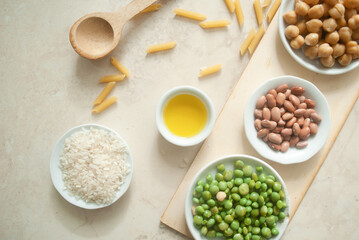 beans, peas, chickpeas, dry pasta, rice, olive oil, and a wooden spoon in a kitchen worktop