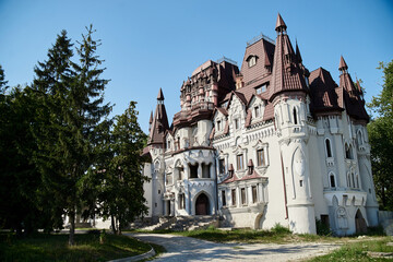 Fototapeta na wymiar Scenic view over whimsical castle with red roof, surrounded by green trees. Beautiful historical landscape. Summer getaway vacation. Architectural sightseeing tour