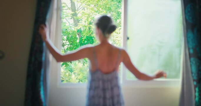 Woman opens the curtains. Young woman opens the authentic curtains and enjoys fresh air coming from tropical garden