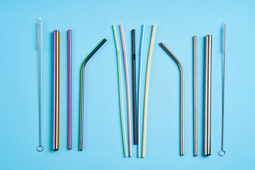 The modern trend towards caring for the environment. Kit of reusable metal beverage straws of various shape and diameters with cleaning tool versus common plastic straws