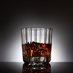 Cyrstal glass of whiskey backlit with ice cubes
