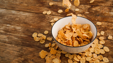Cereals falling in a white bowl on a wooden table