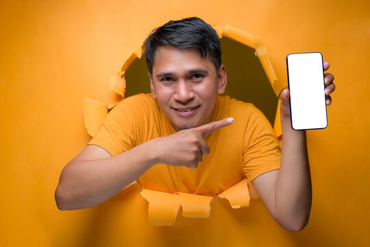 A Casual Asian man pointing a mobile phone with blank white screen display, on paper hole