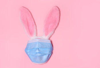 Pink bunny rabbit with face protective mask on pink background. Easter quarantine concept.Copy space for text, top view, flat lay