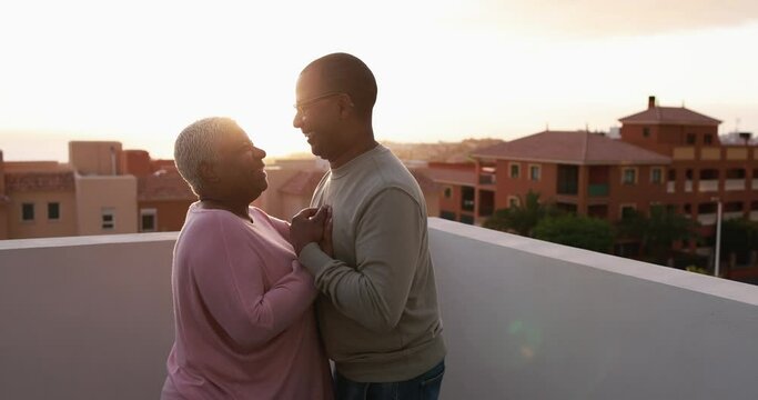 Happy senior couple dancing outdoor on patio home at sunset - Love and joyful elderly lifestyle concept 