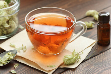 Hop herbal tea with dry herb on wooden table, natural decoction is used against insomnia, depression and for menopause and skin, hair care, closeup, copy space, natural medicine, naturopathy concept
