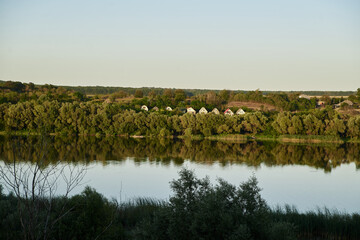 Scenic view over wide river and it's bank. Beautiful natural countryside landscape at sunset. Summer getaway vacation into isolated places. Calm water - perfect for meditation.