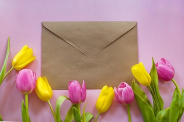 Tulips and envelope on pink background, copy space. Card for Mother's Day or Valentine's day on pink background. 
