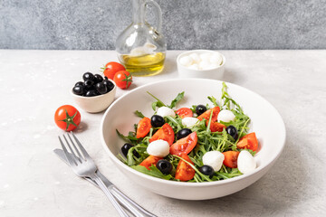 Mediterranean diets food. Mozzarella salad with tomatoes black olives arugula and olive oil. dish of Italian Greek cuisine. Healthy eating